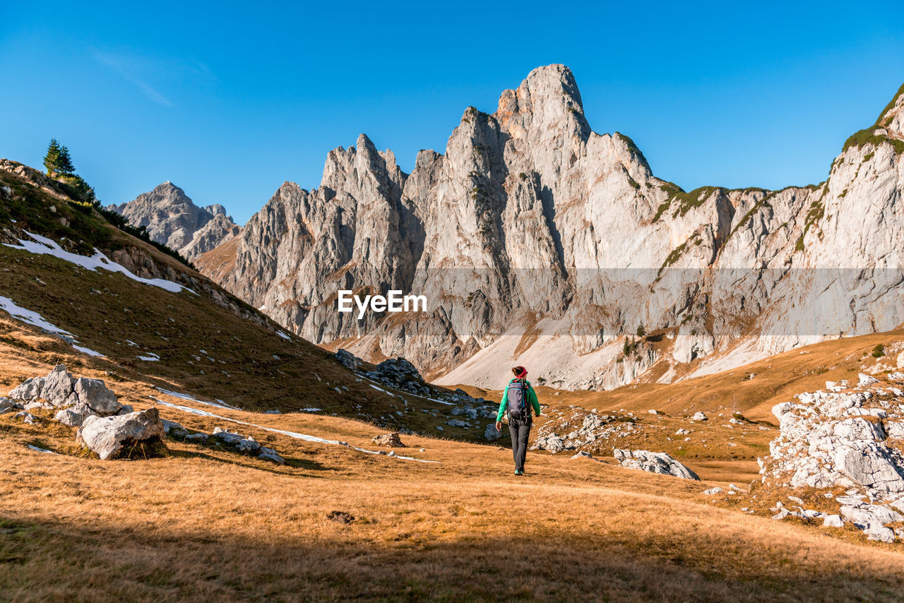 Woman hiking on footpath in alpine landscape in autumn, bischofsmütze, filzmoos, austria