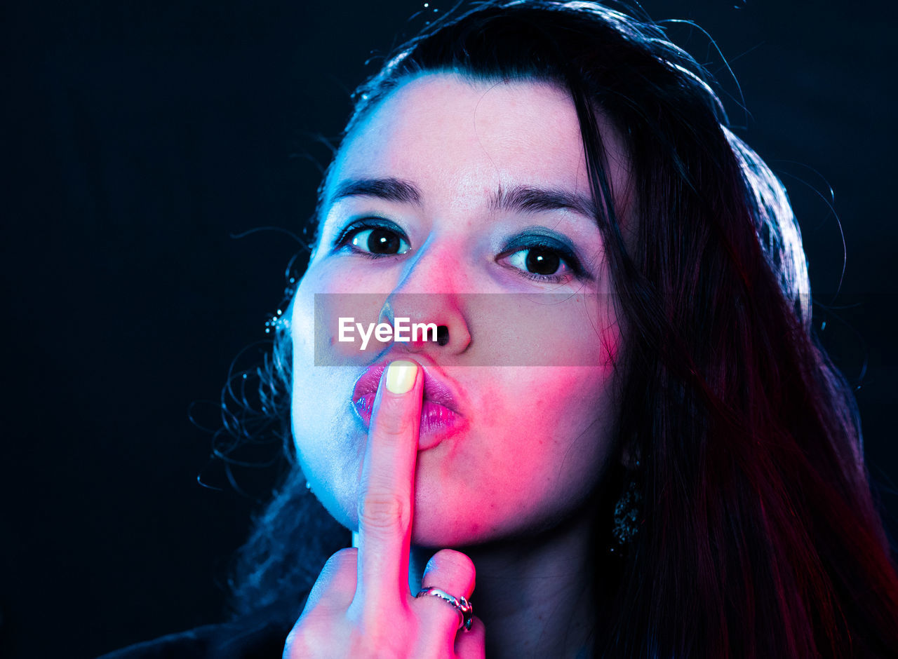 Portrait of young woman gesturing obscene gesture at nightclub