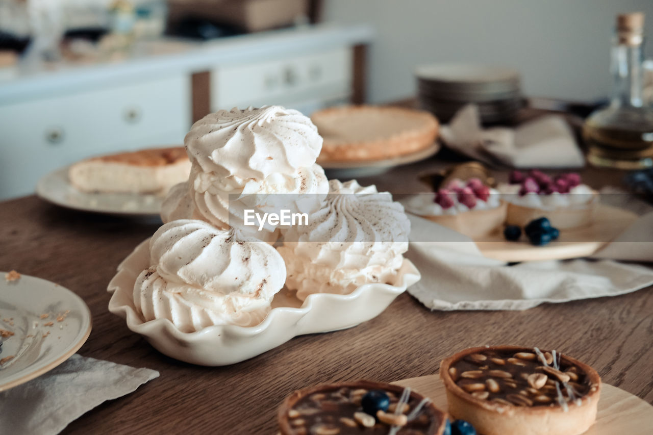 White airy meringue cake on the festive table, in the kitchen.