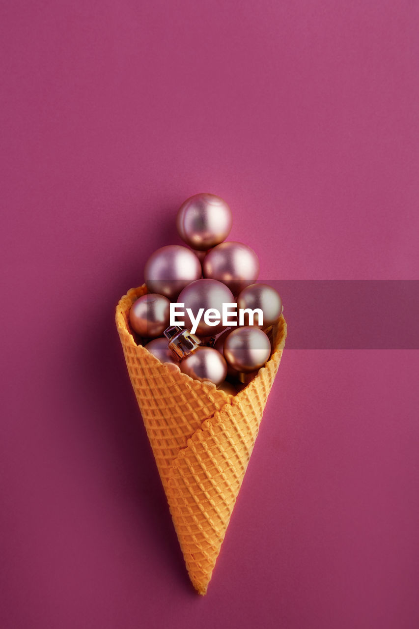 Directly above shot of ice cream cone with bauble over green background