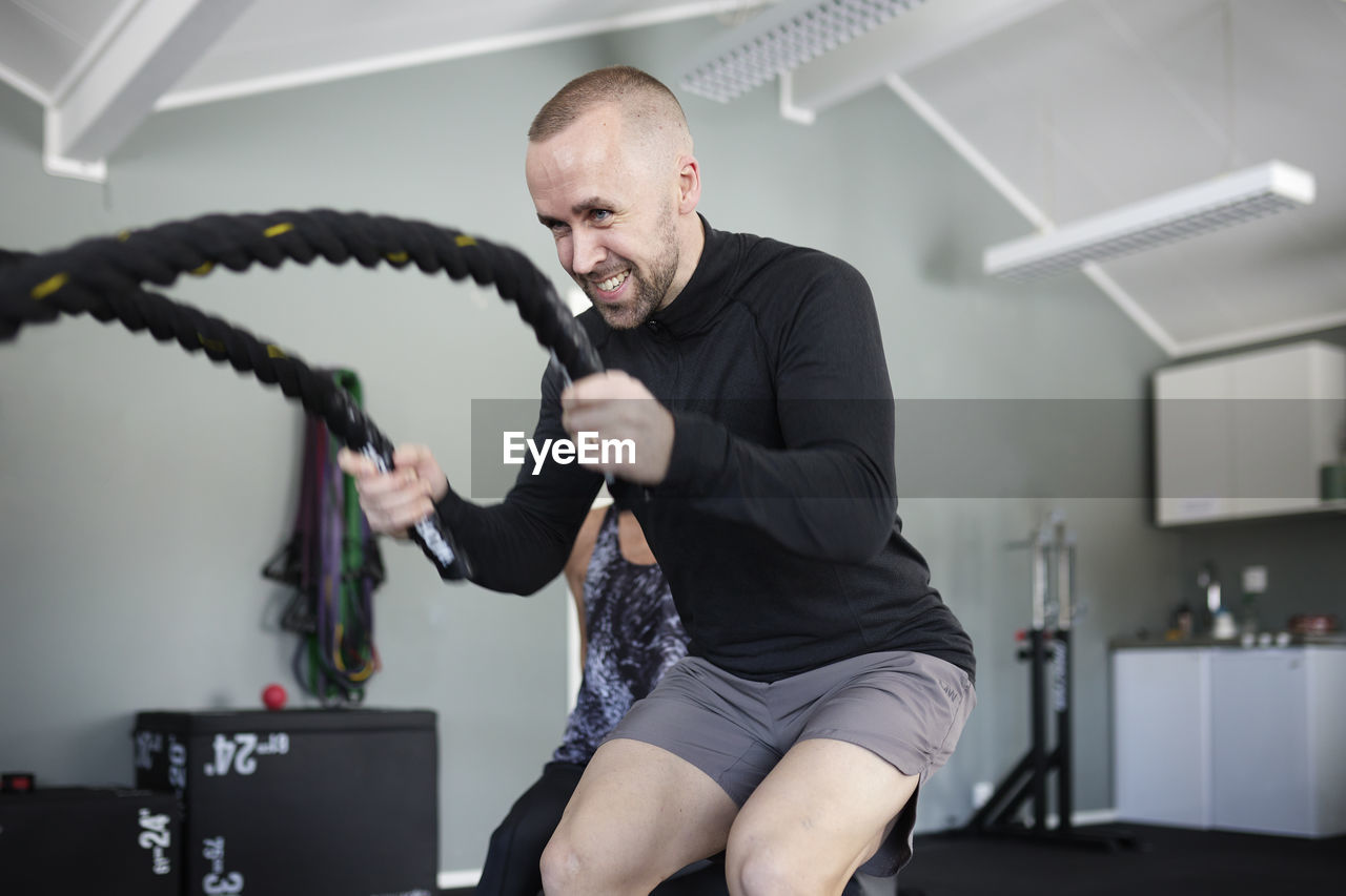 Man exercising with ropes in gym