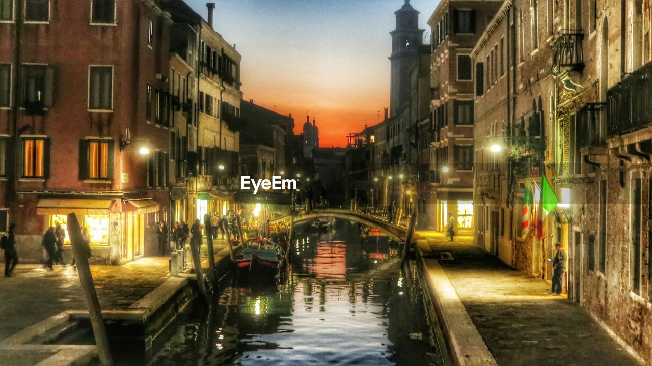 Canal amidst buildings in city at dusk