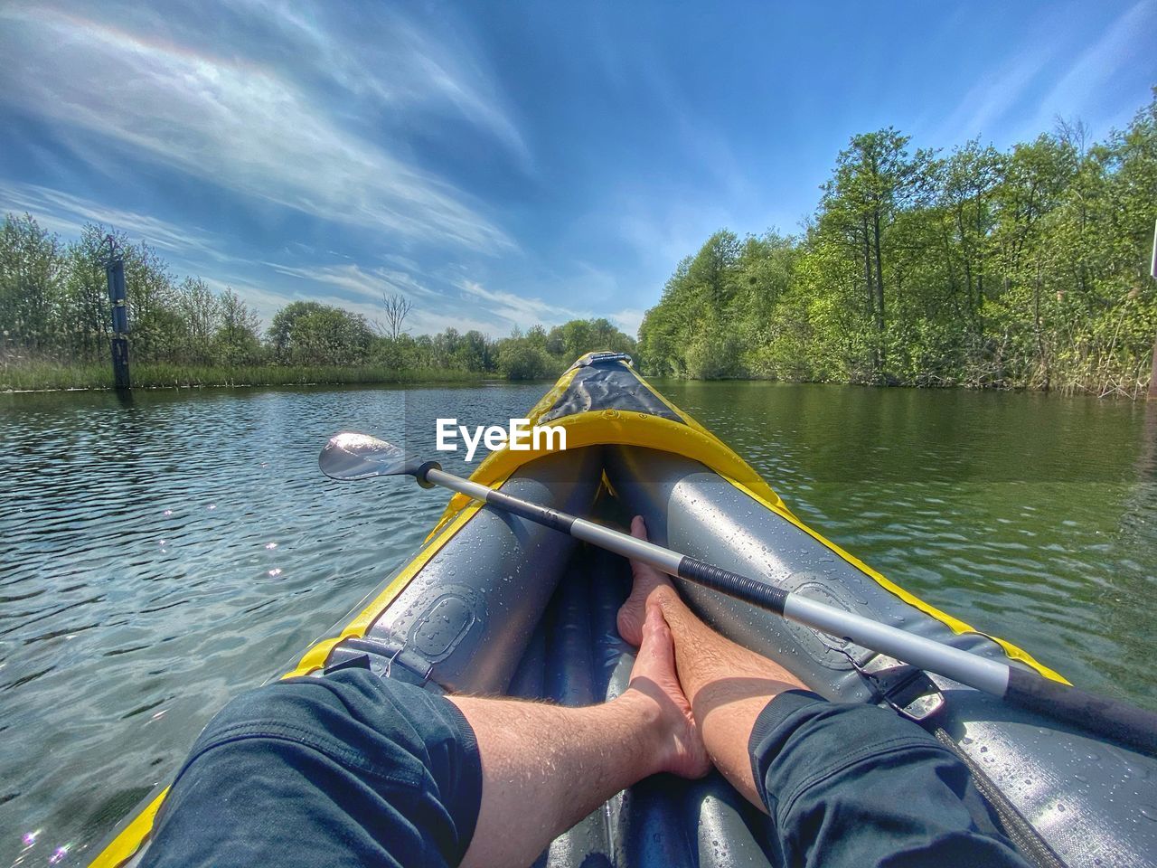 Low section of person in boat on lake against sky