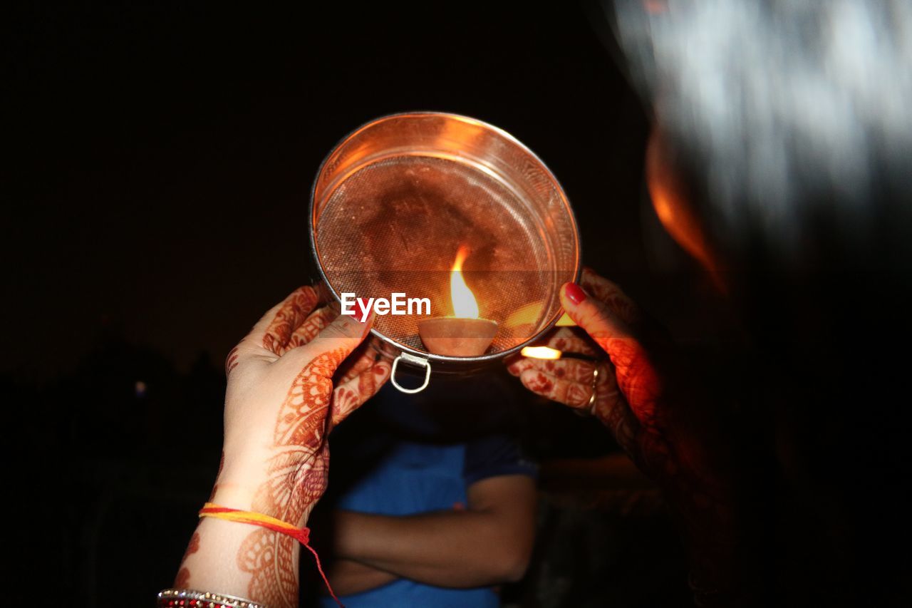 Cropped image of woman holding colander against man at night