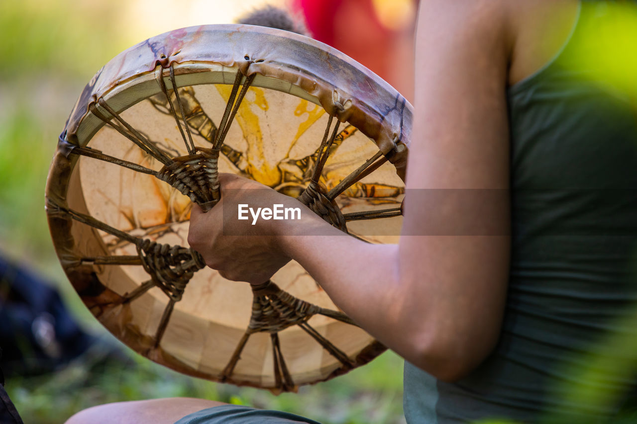 Midsection of man holding tribal drum outdoors