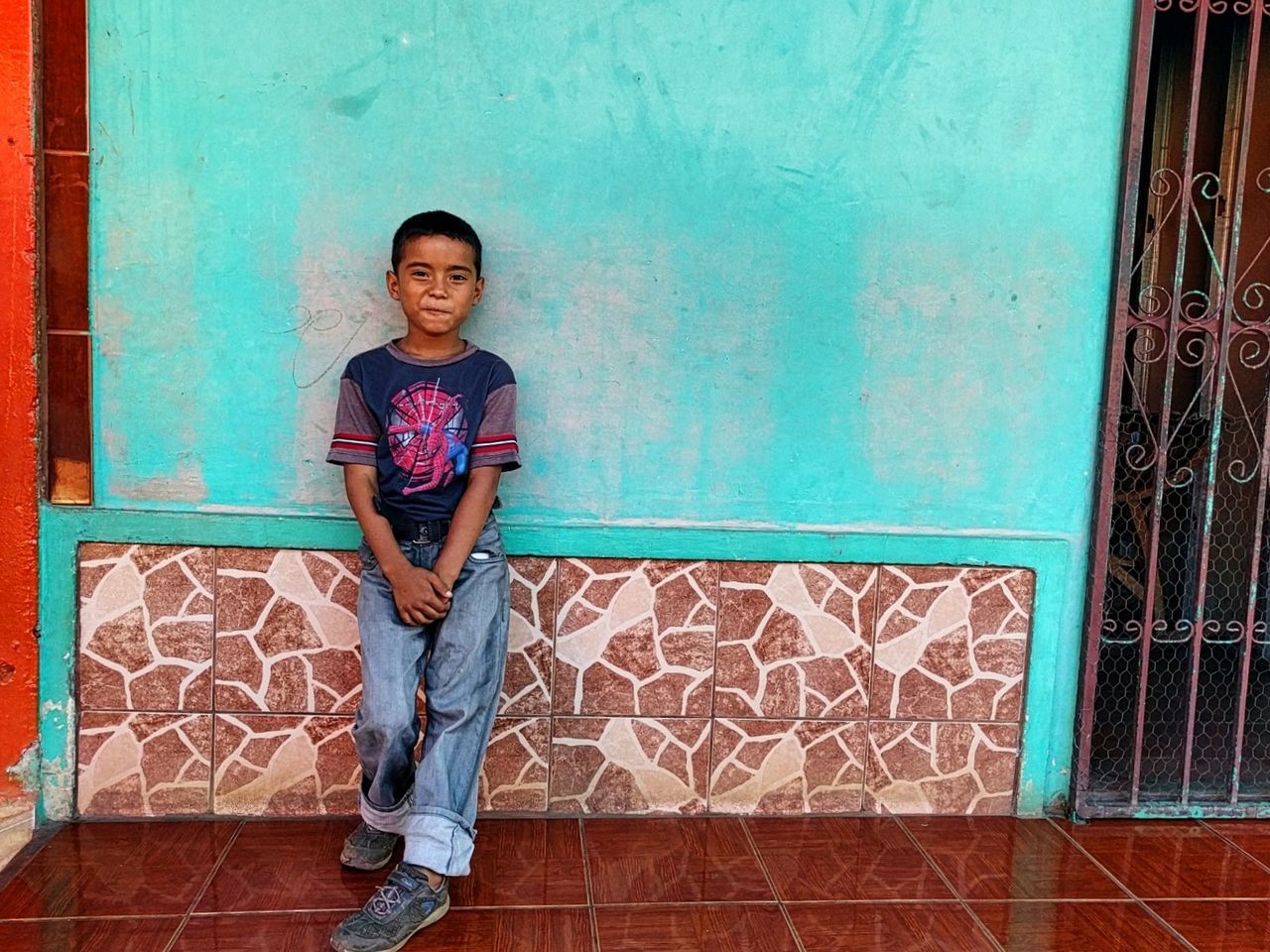 PORTRAIT OF HAPPY GIRL LEANING AGAINST WALL