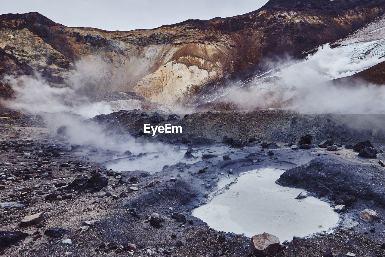 Smoke emitting from hot springs against mountains