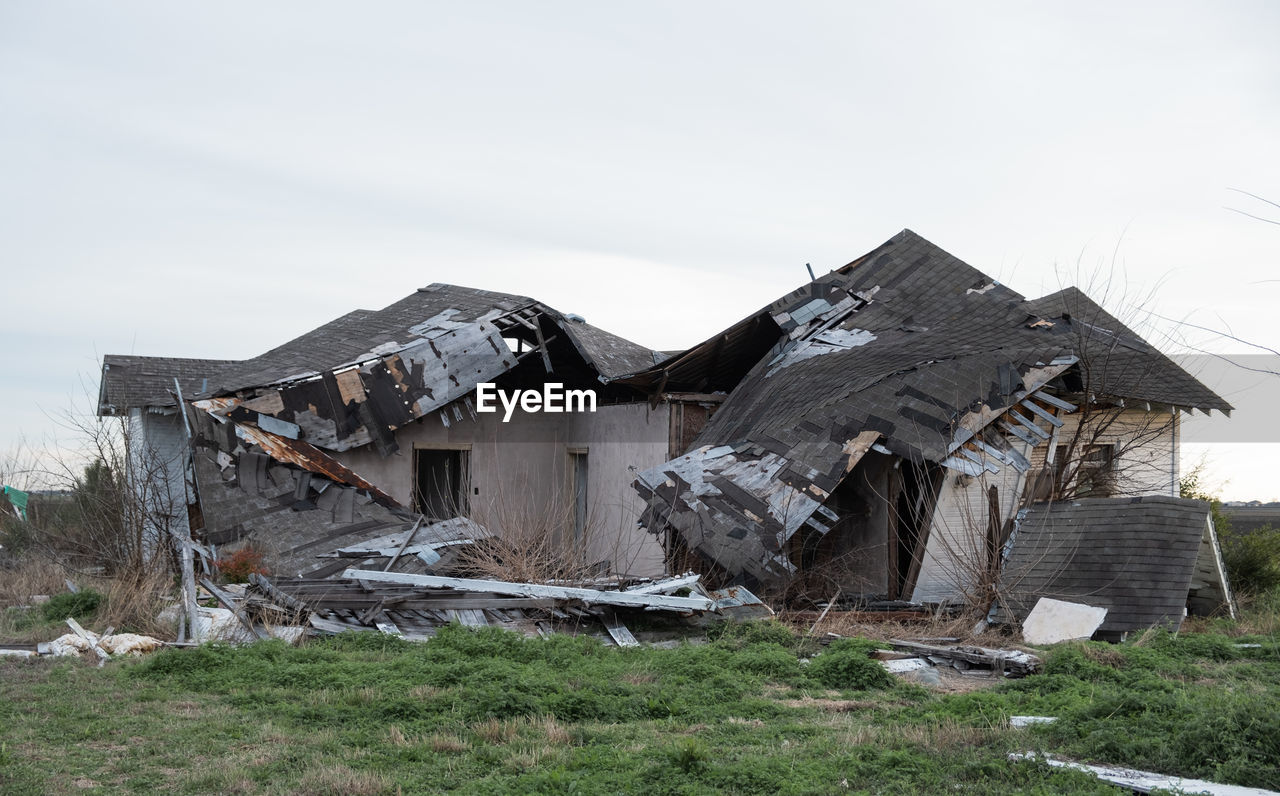 ABANDONED BUILDINGS ON FIELD AGAINST SKY