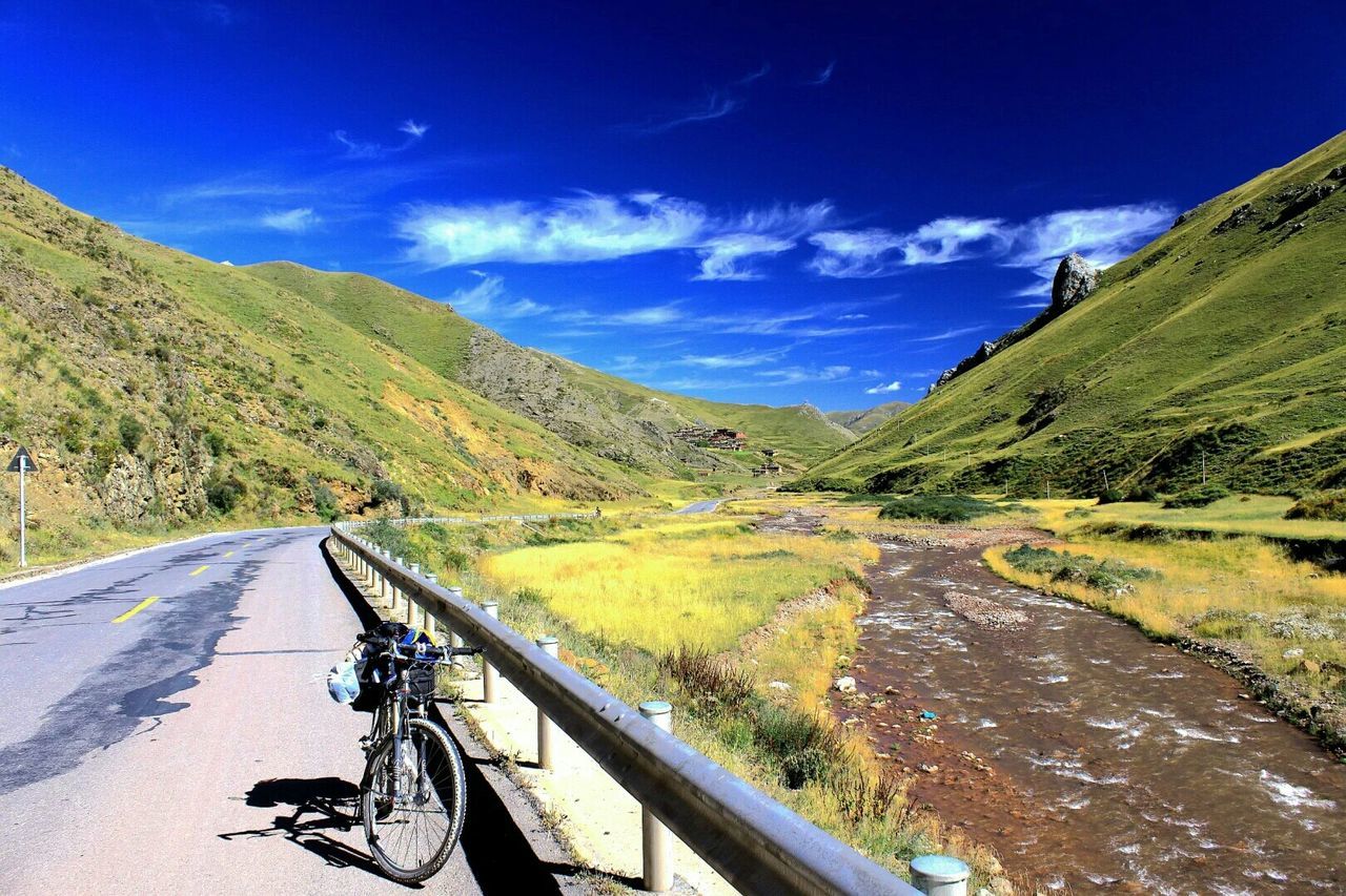 Scenic view of road by mountains against sky