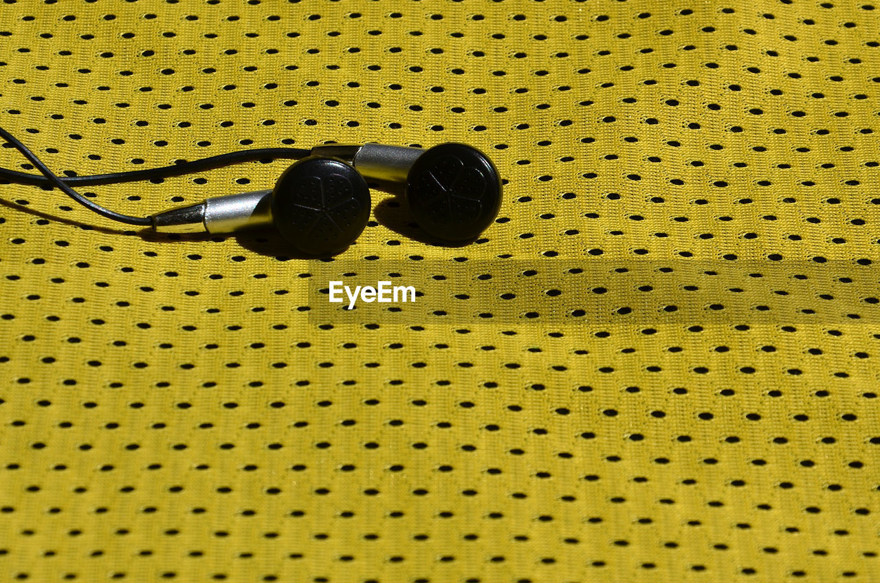 High angle view of earphones on yellow fabric