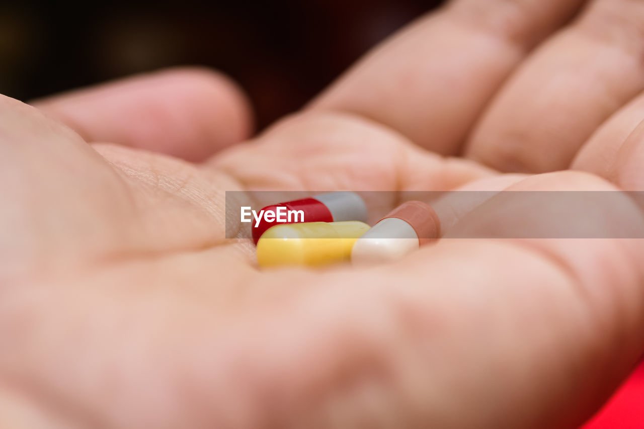 Close-up of hand holding multi colored capsules