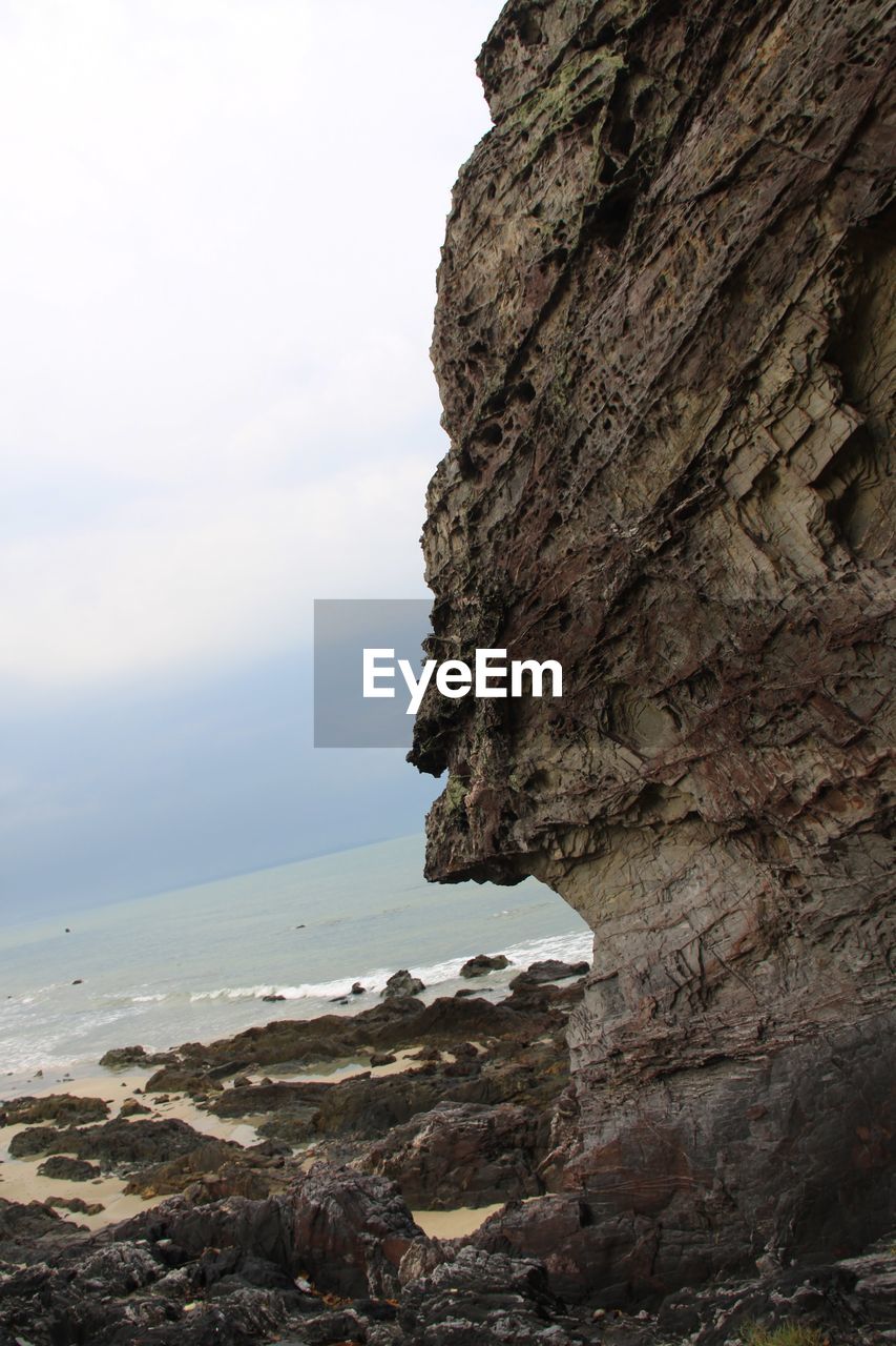 CLOSE-UP OF ROCK FORMATION AGAINST SEA