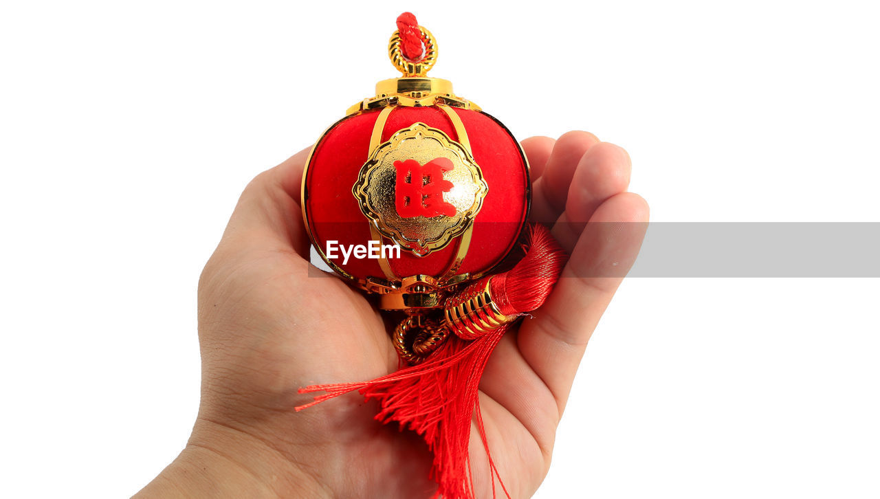 CLOSE-UP OF WOMAN HOLDING RED OVER WHITE BACKGROUND