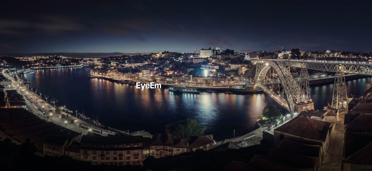 Aerial view of arch bridge over river against sky at night