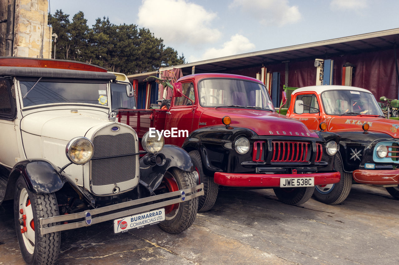 motor vehicle, car, mode of transportation, transportation, antique car, vehicle, land vehicle, vintage car, luxury vehicle, architecture, cloud, red, retro styled, city, transport, sky, truck, street, day, outdoors
