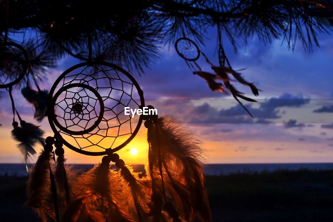 Close-up of dreamcatcher against sky during sunset