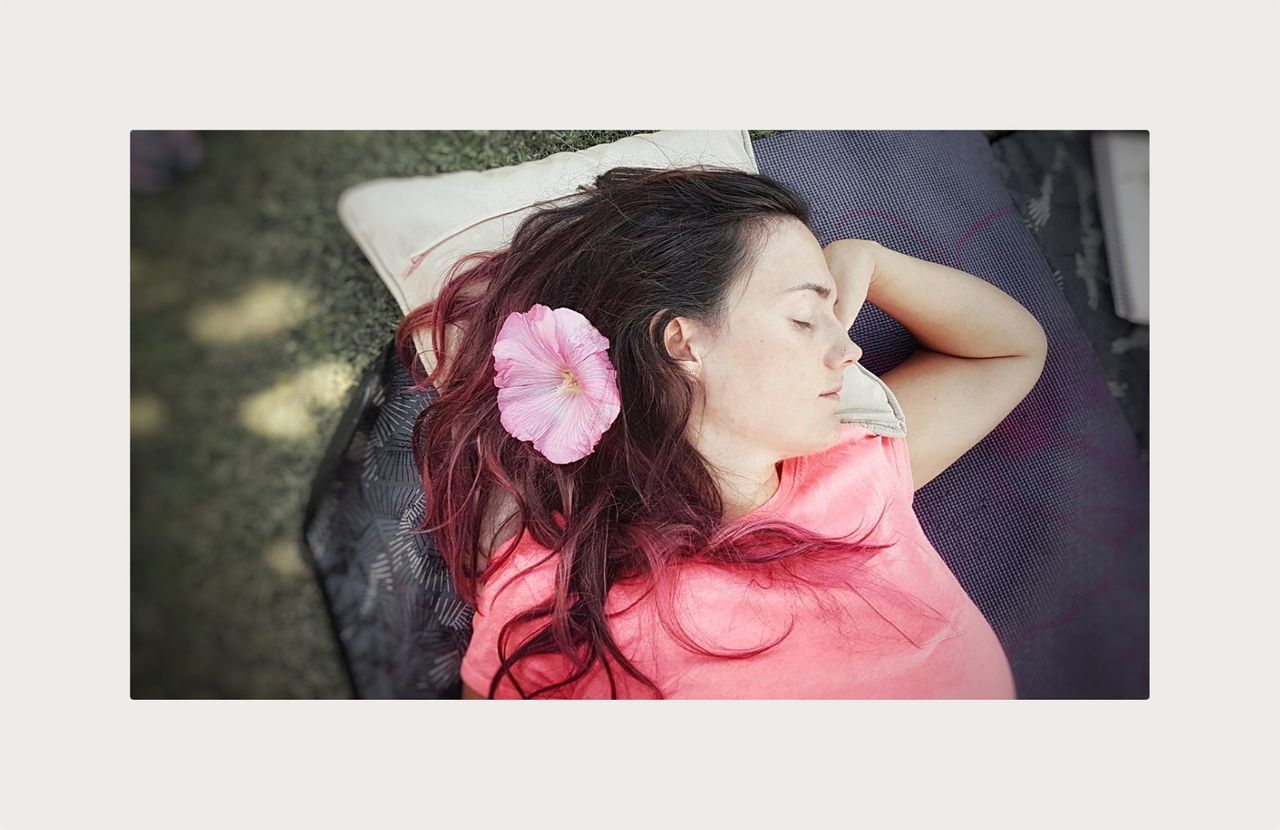 PORTRAIT OF YOUNG WOMAN LYING DOWN ON PINK FACE