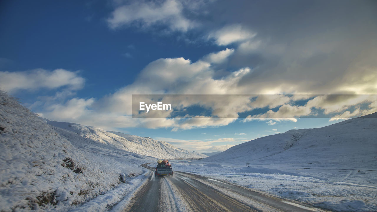 Road amidst snow covered mountains against sky