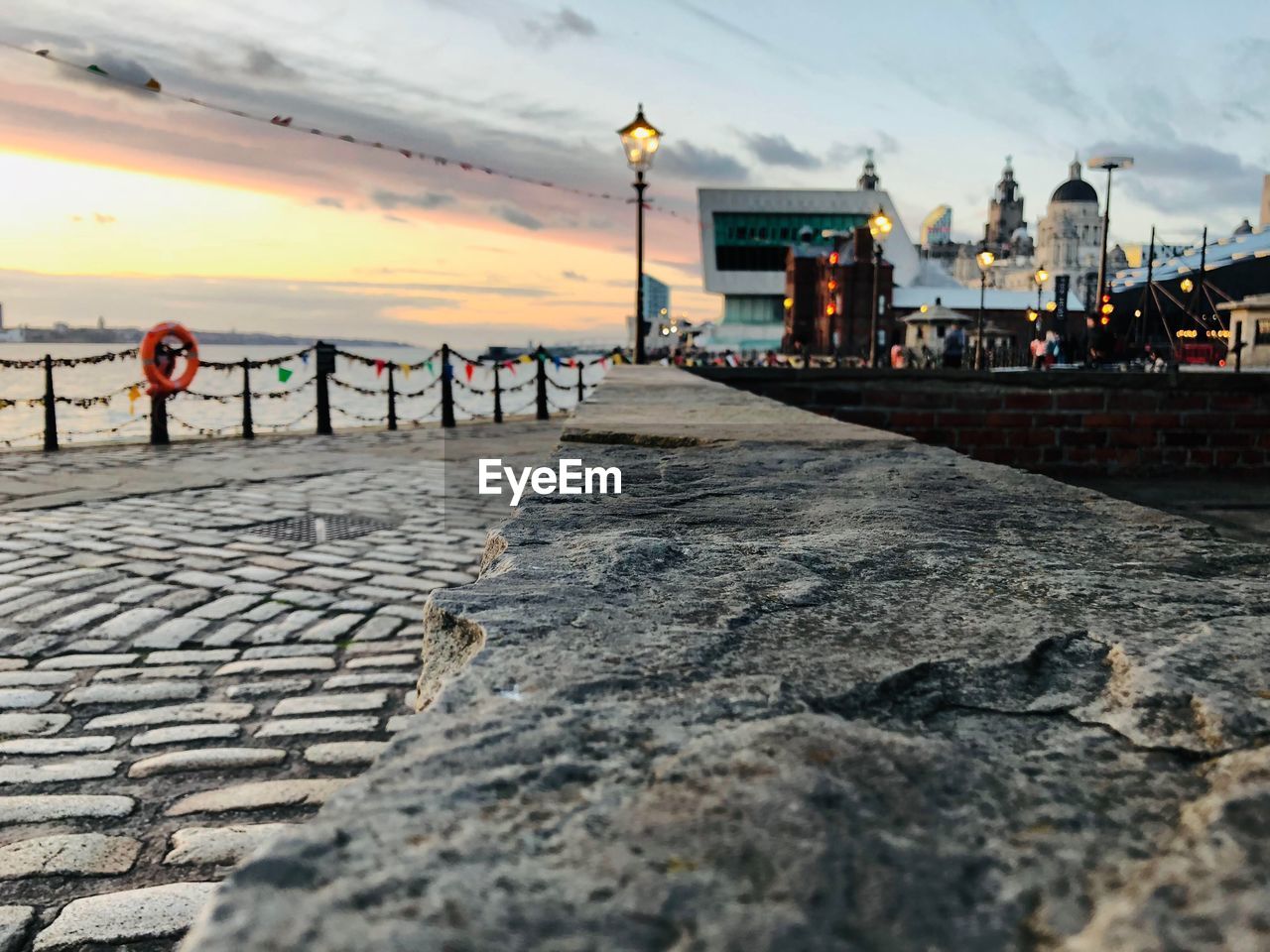 View of footpath in city at sunset