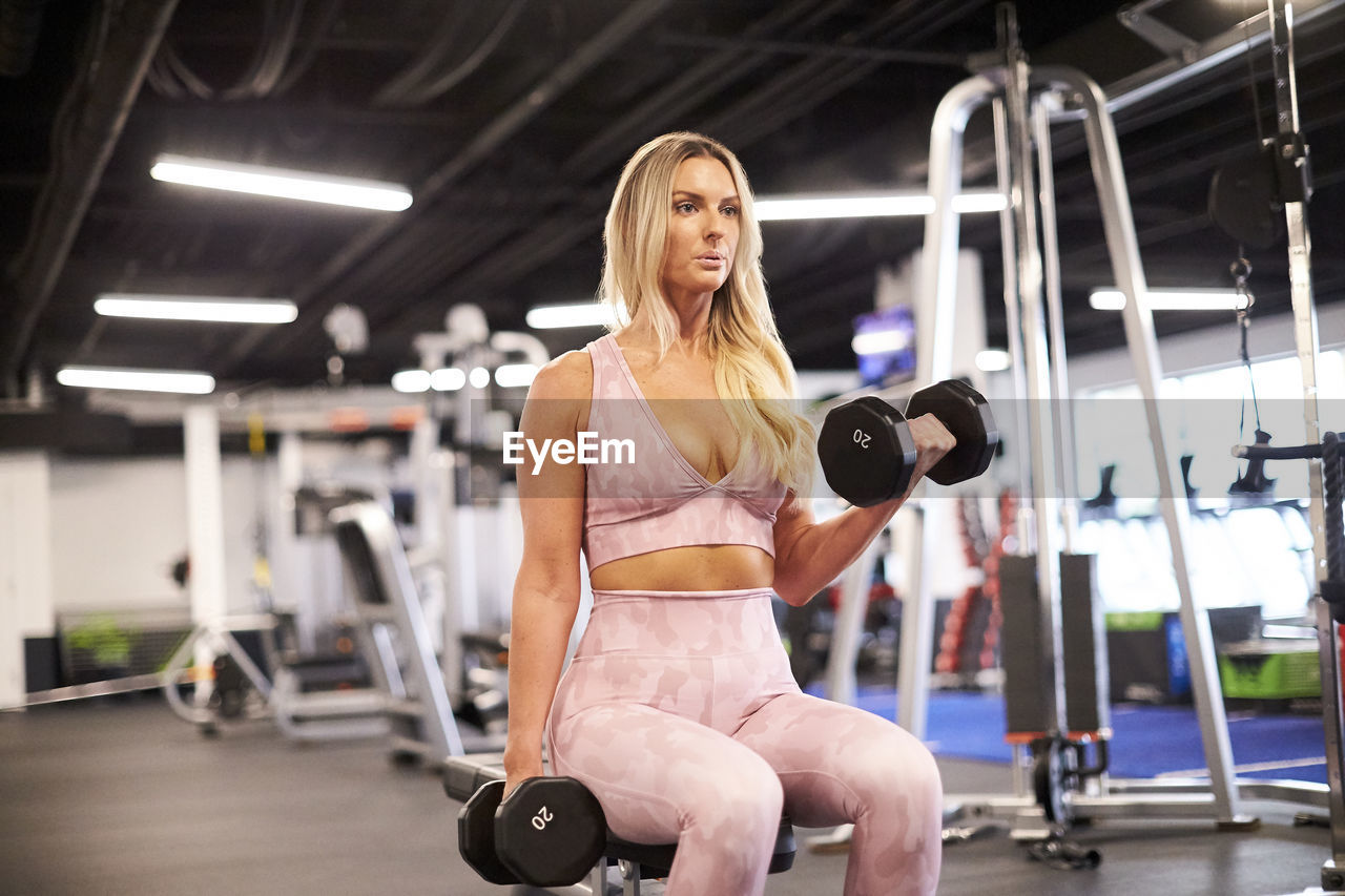 A blonde woman doing bicep curls at the gym.
