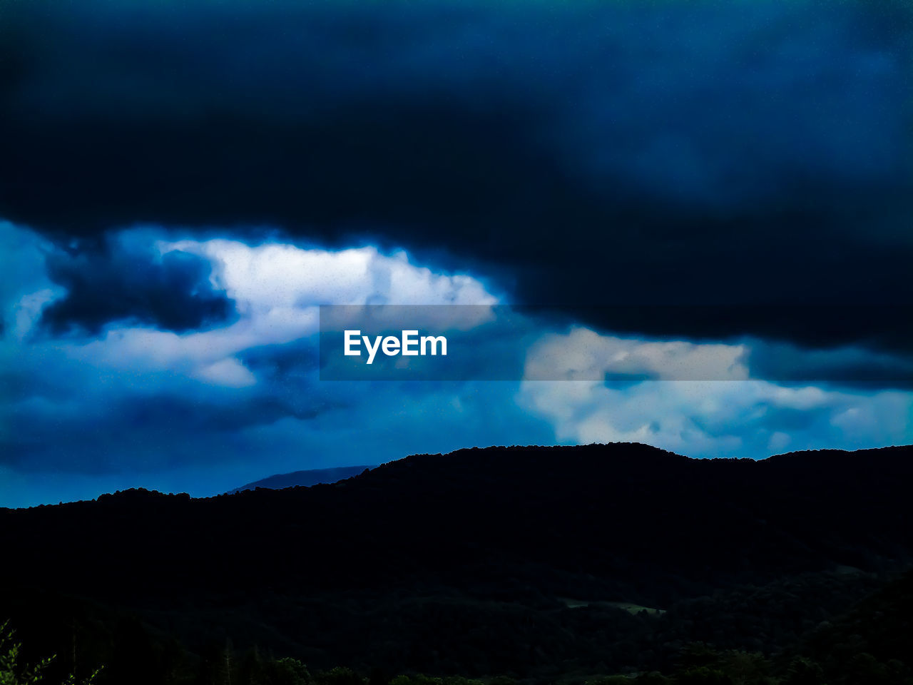 LOW ANGLE VIEW OF SILHOUETTE MOUNTAIN AGAINST CLOUDY SKY