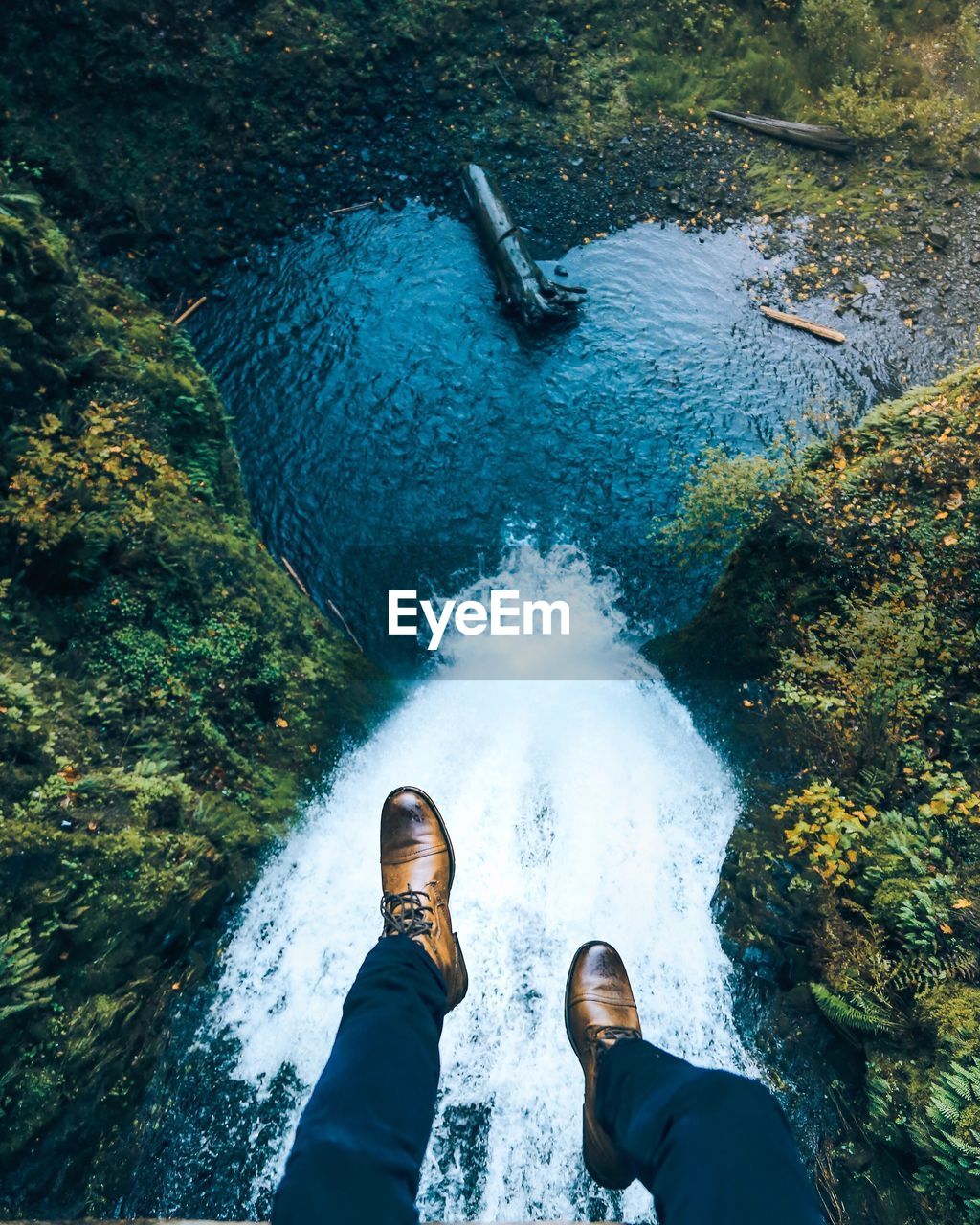 Low section of man sitting above river