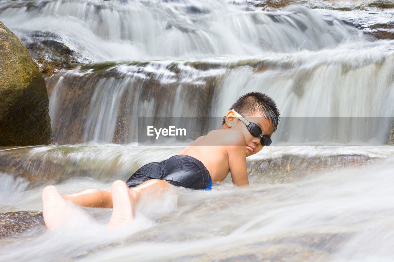 Portrait of boy enjoying in waterfall