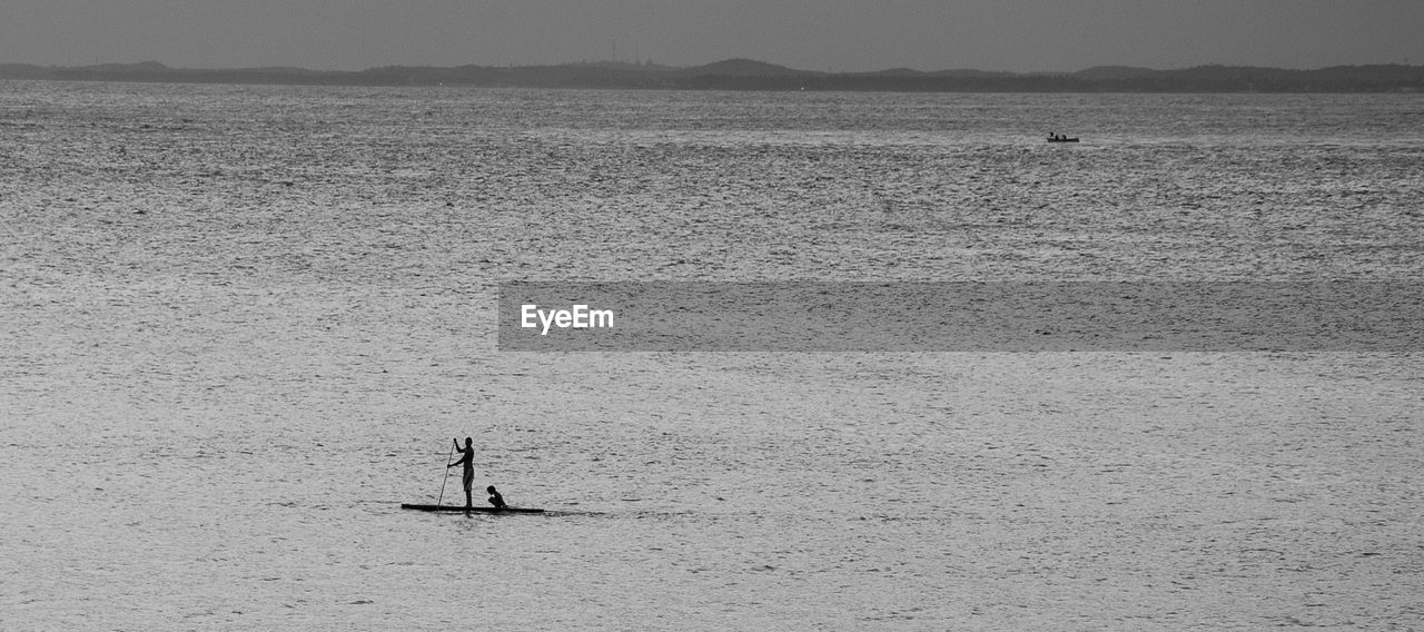 Distant view of man sailing boat in sea