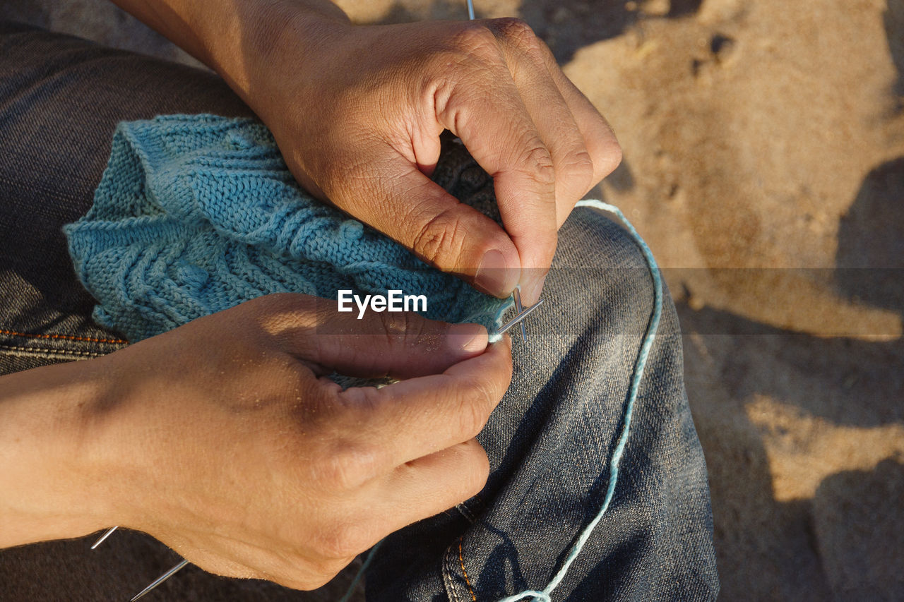 Midsection of man knitting outdoors