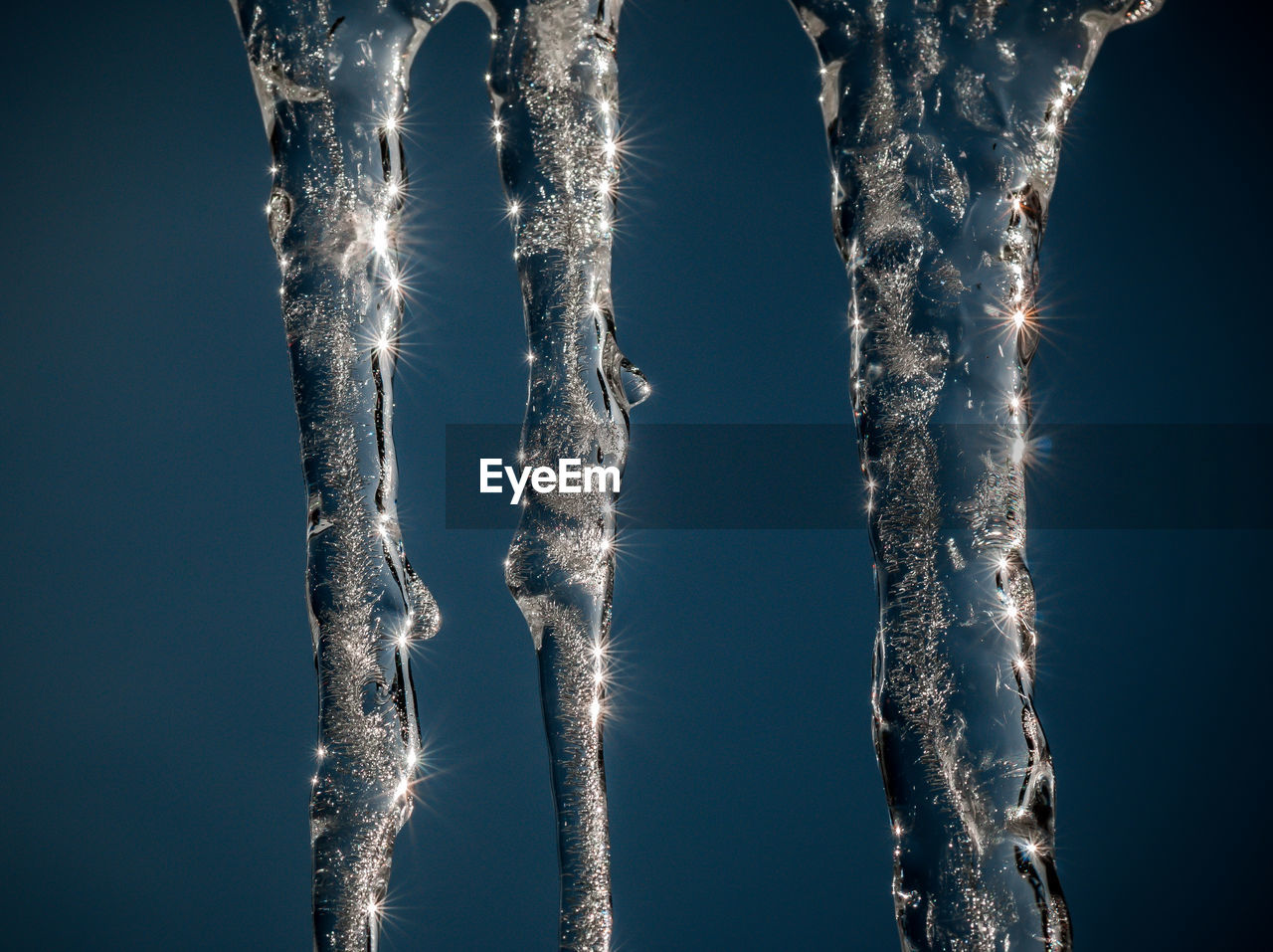 Close-up of icicles against blue sky