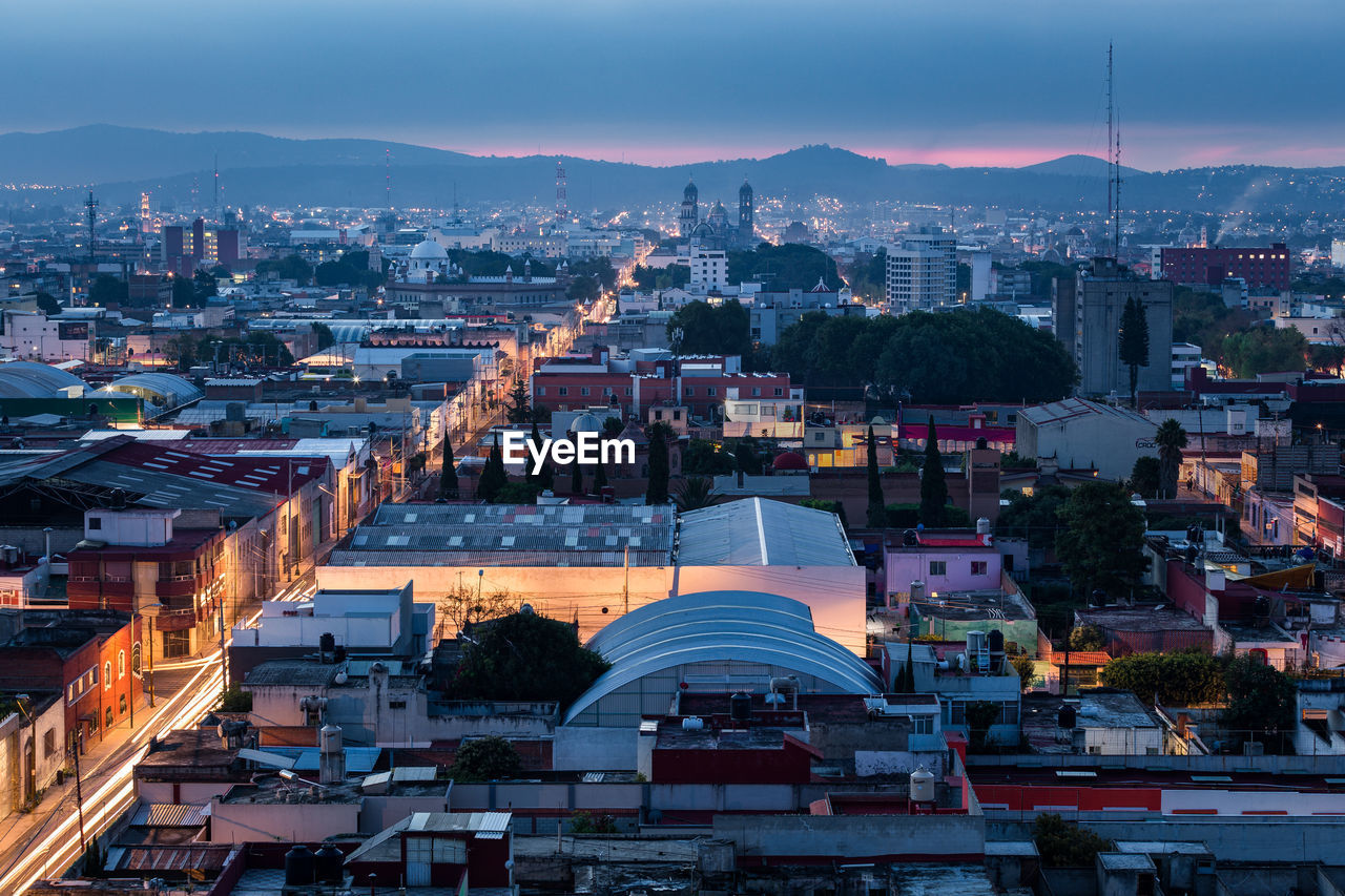 HIGH ANGLE VIEW OF ILLUMINATED CITY BUILDINGS AGAINST SKY