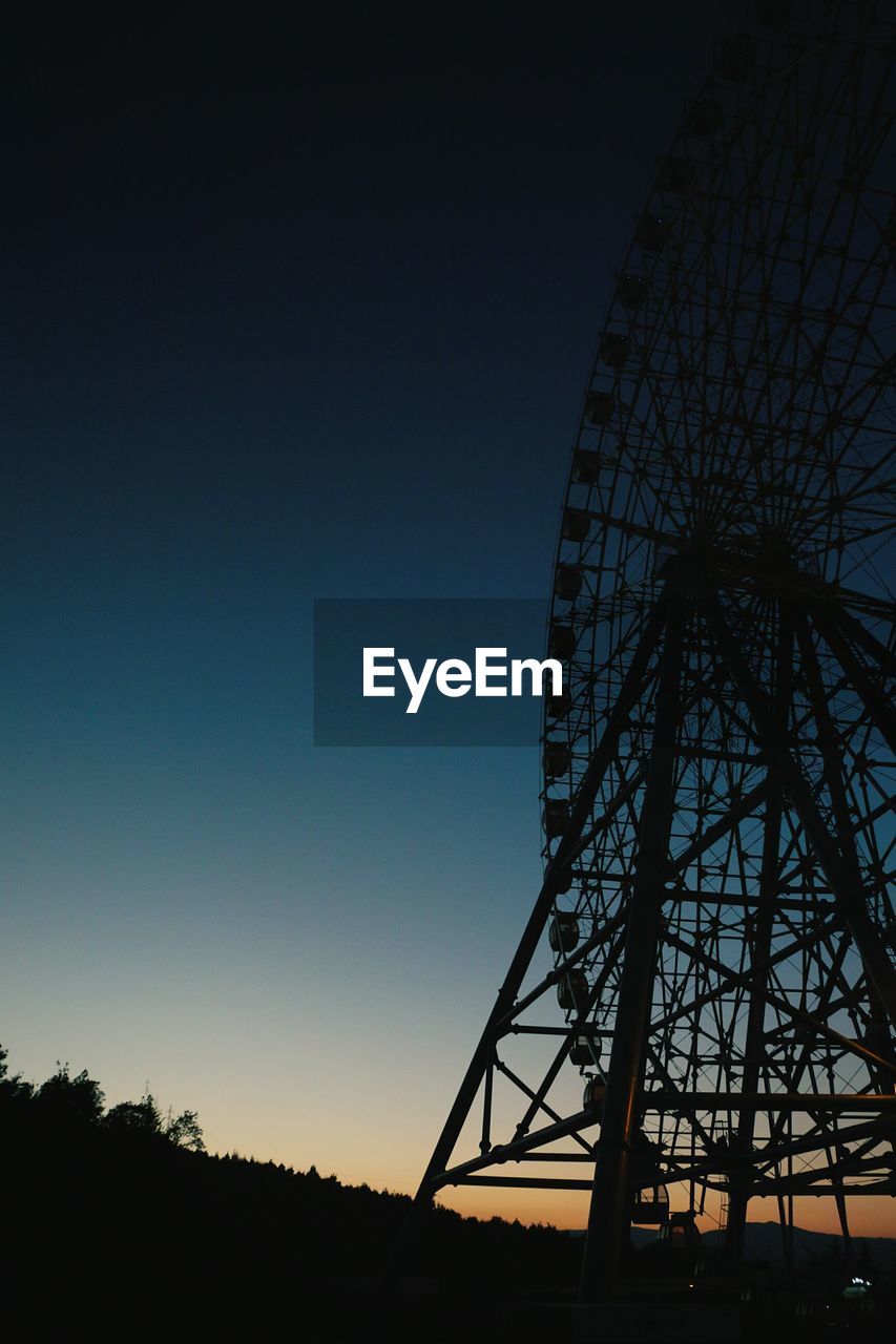 Low angle view of silhouette ferris wheel against clear sky