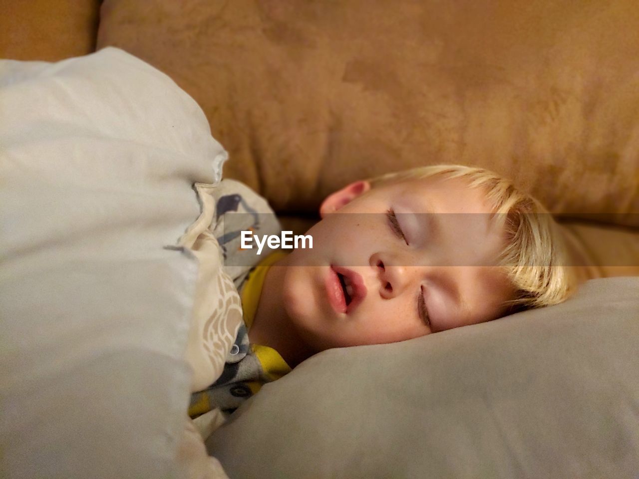 Cute blonde boy sleeping on bed 