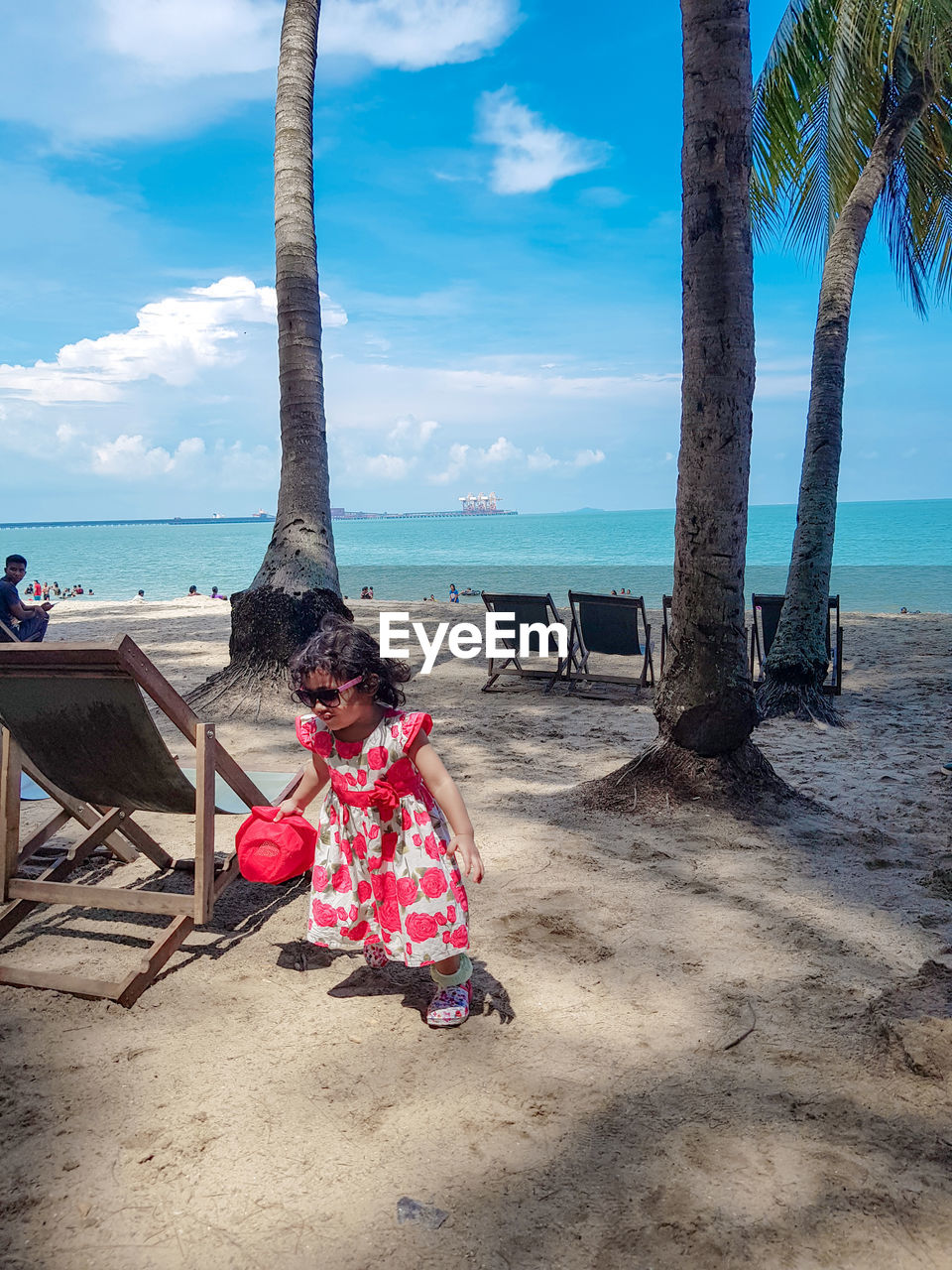 WOMAN SITTING ON TREE BY SEA AGAINST SKY