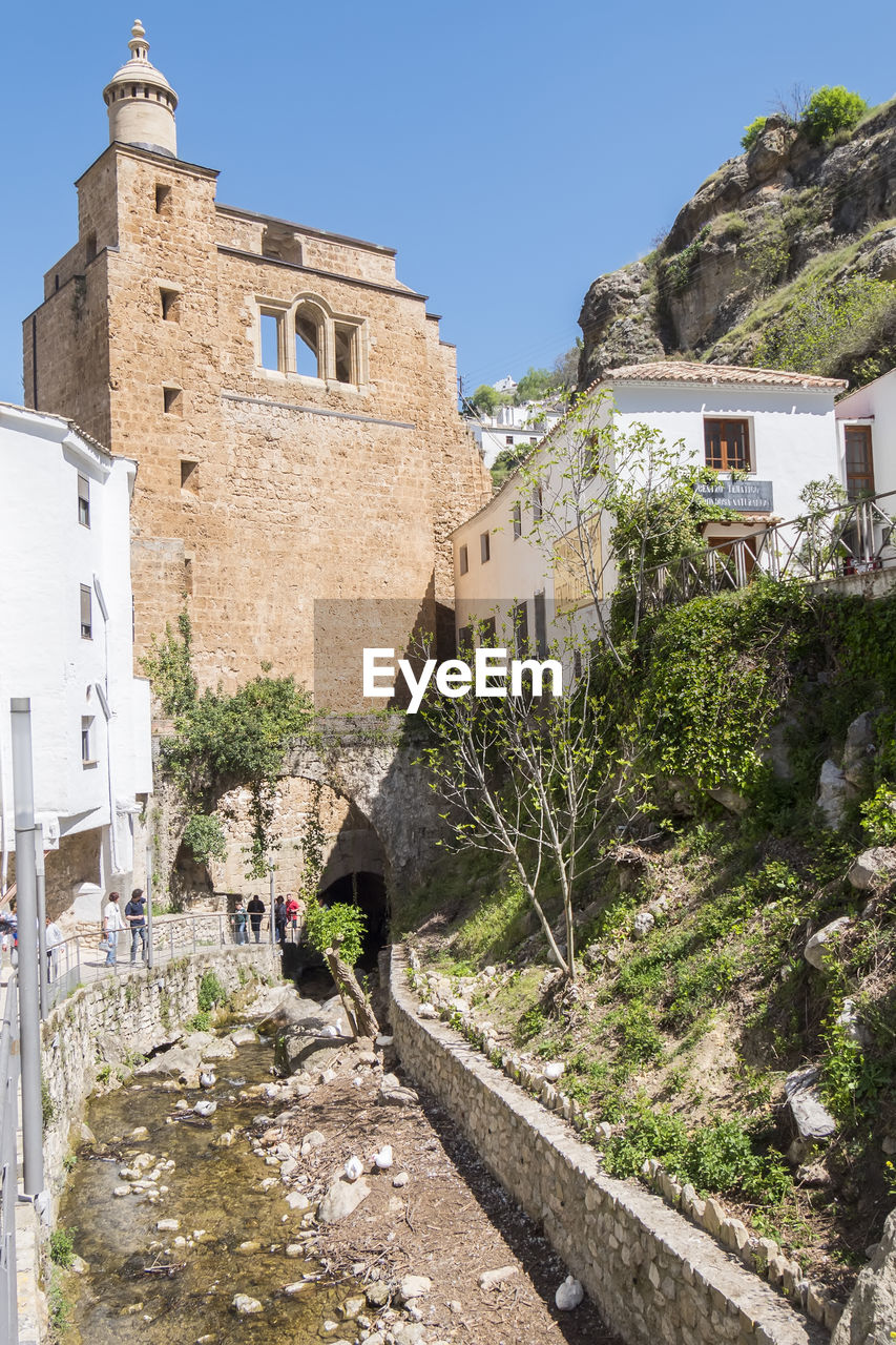 architecture, building exterior, built structure, building, village, town, nature, sky, clear sky, travel destinations, history, travel, the past, tourism, sunny, plant, day, city, fortification, ancient history, house, vacation, wall, residential district, outdoors, old, sunlight, tree, religion, blue, no people, fort, place of worship, tower, land, mountain, ruins, holiday