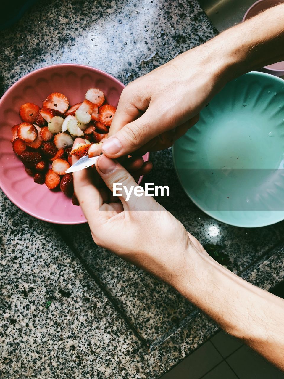 Cropped hands cutting strawberries at table