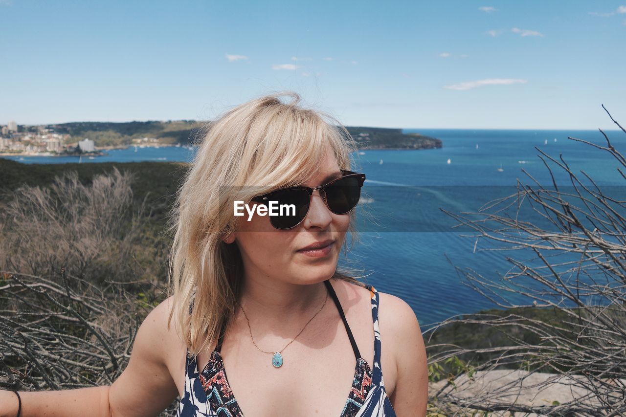 Young woman wearing sunglasses against sea at beach