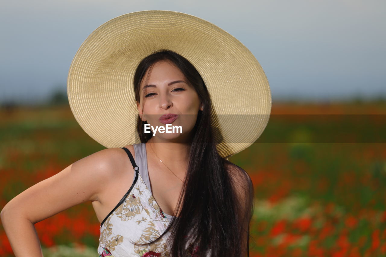 Portrait of young woman standing at poppy farm