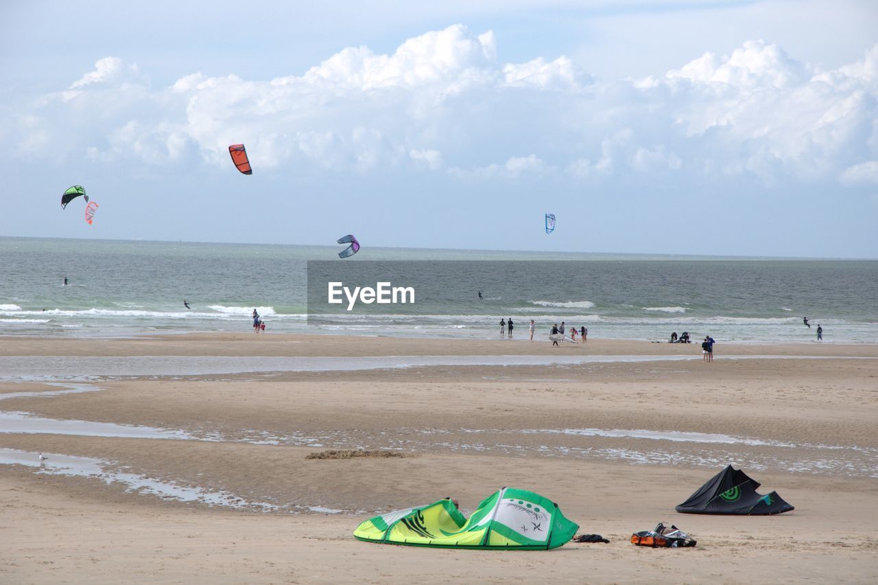 People kiteboarding on sea shore against sky