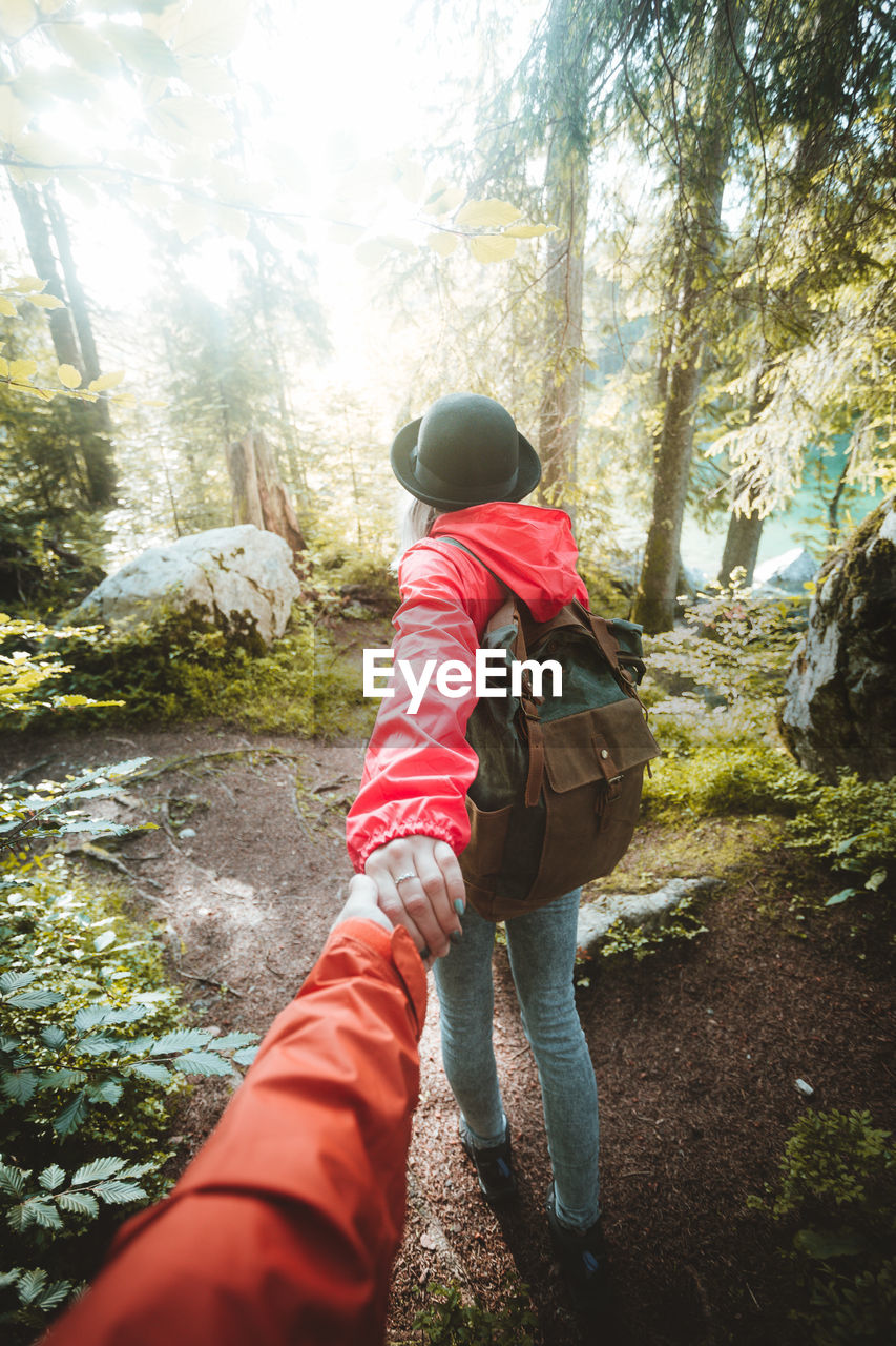 Woman holding hands of man while walking in forest