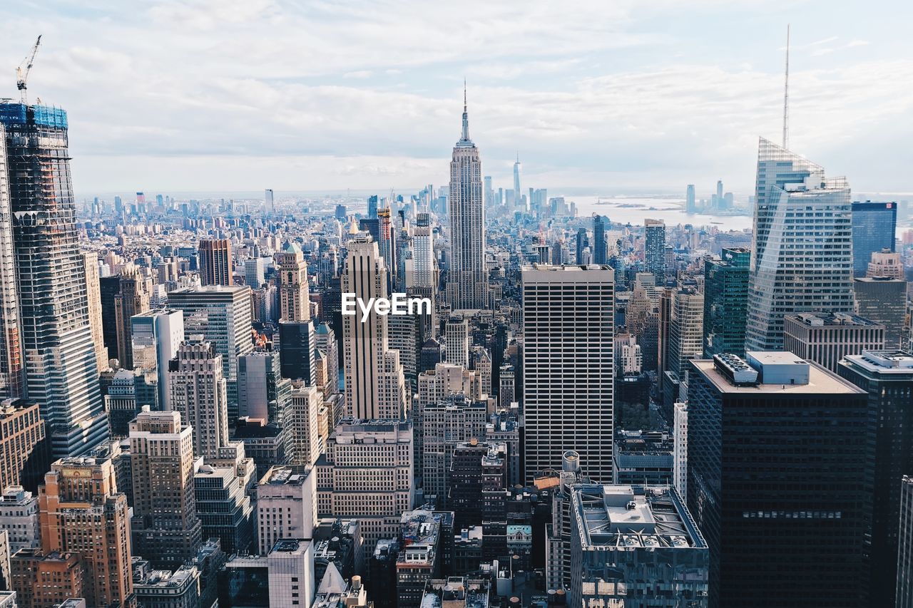 Aerial view of buildings in city against cloudy sky