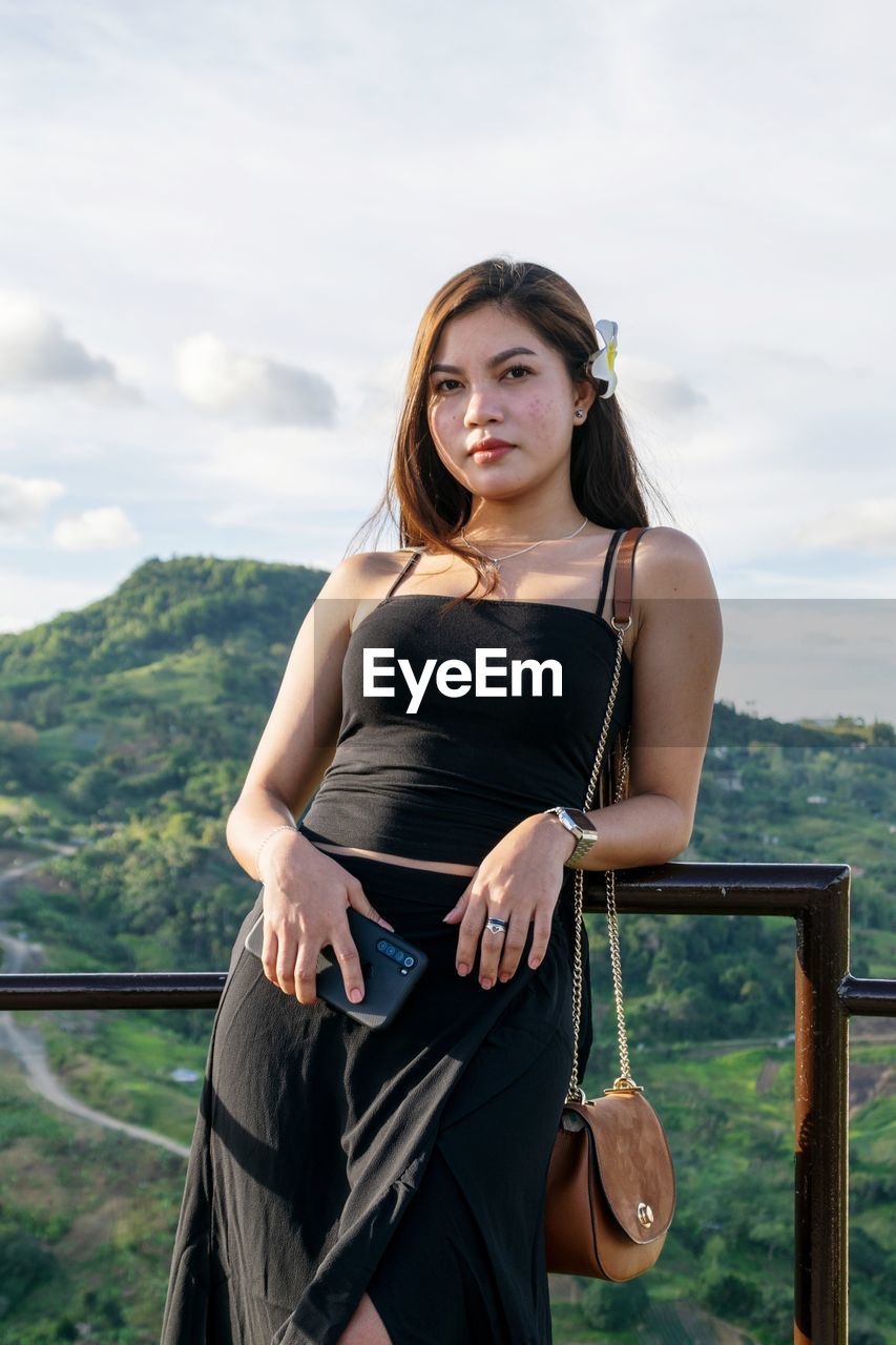 Portrait of woman standing against railing