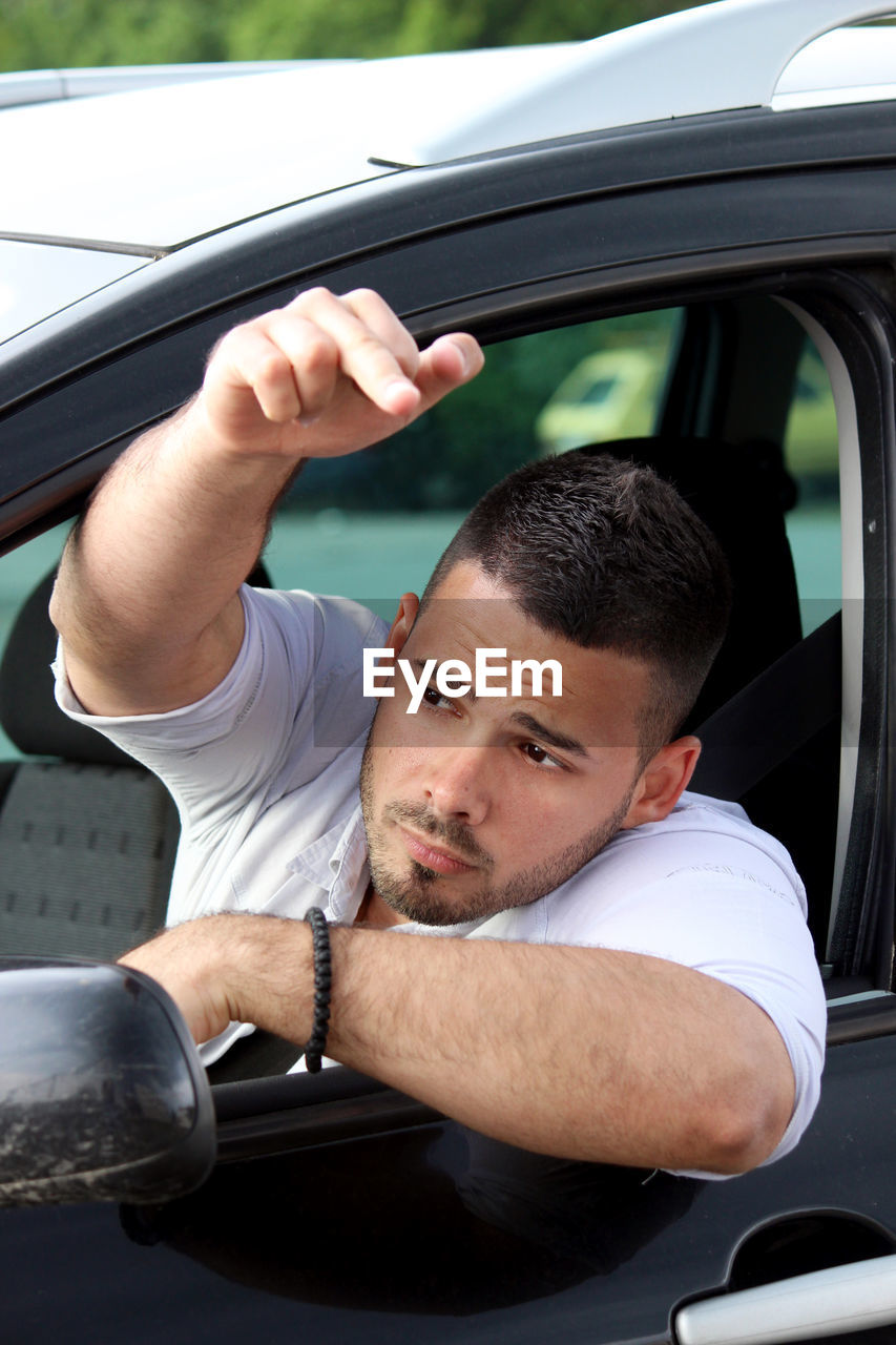 Man showing middle finger through car window