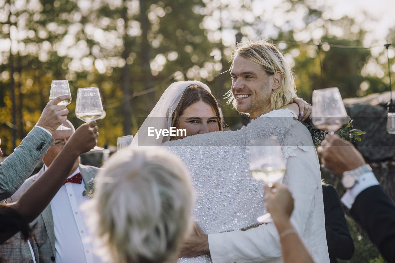 Smiling newlywed couple dancing amidst family and friends at wedding