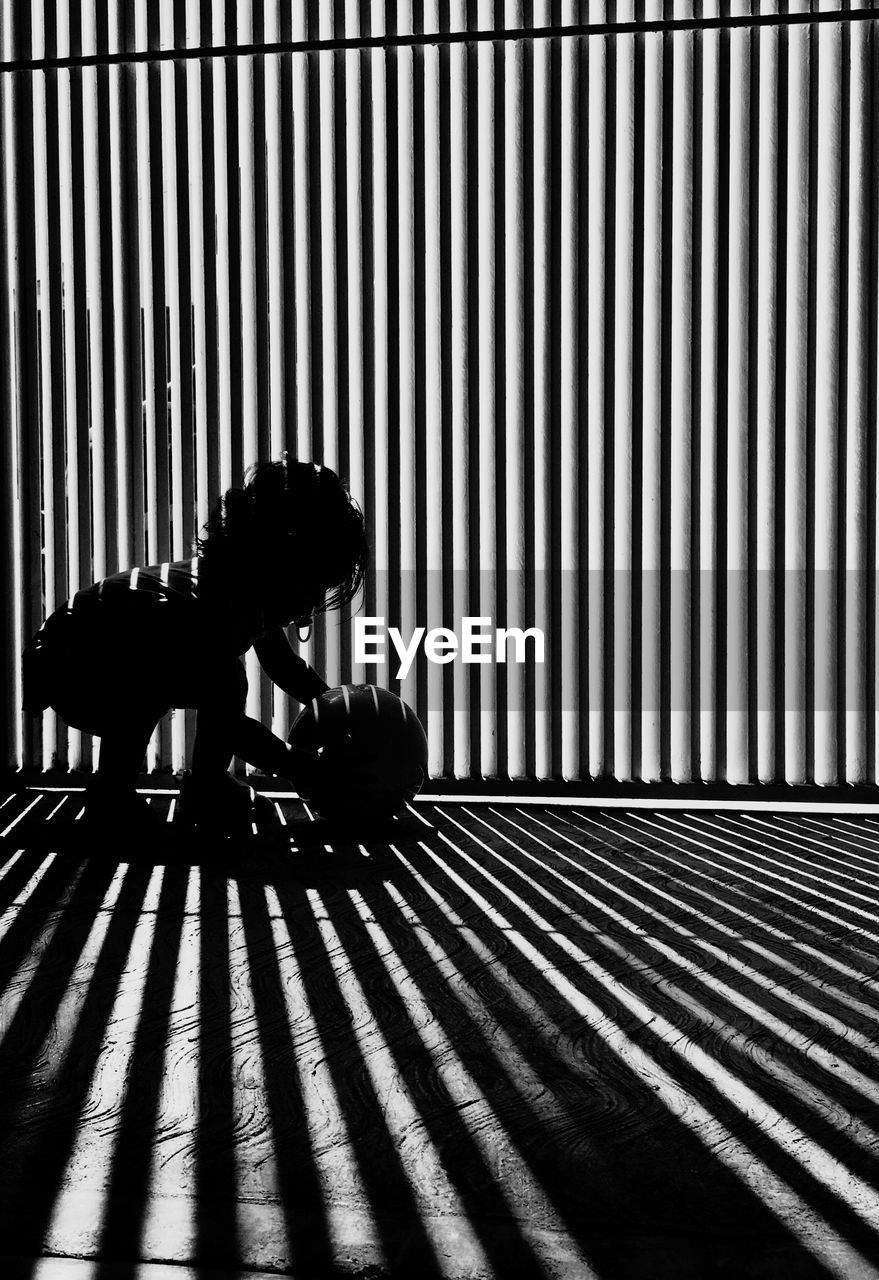 Child playing with ball by blinds