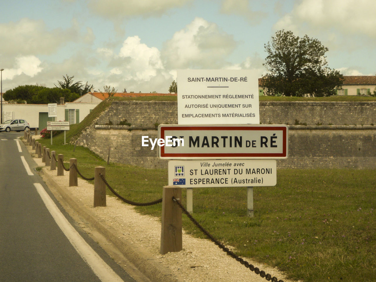 INFORMATION SIGN ON ROAD BY TREES AGAINST SKY