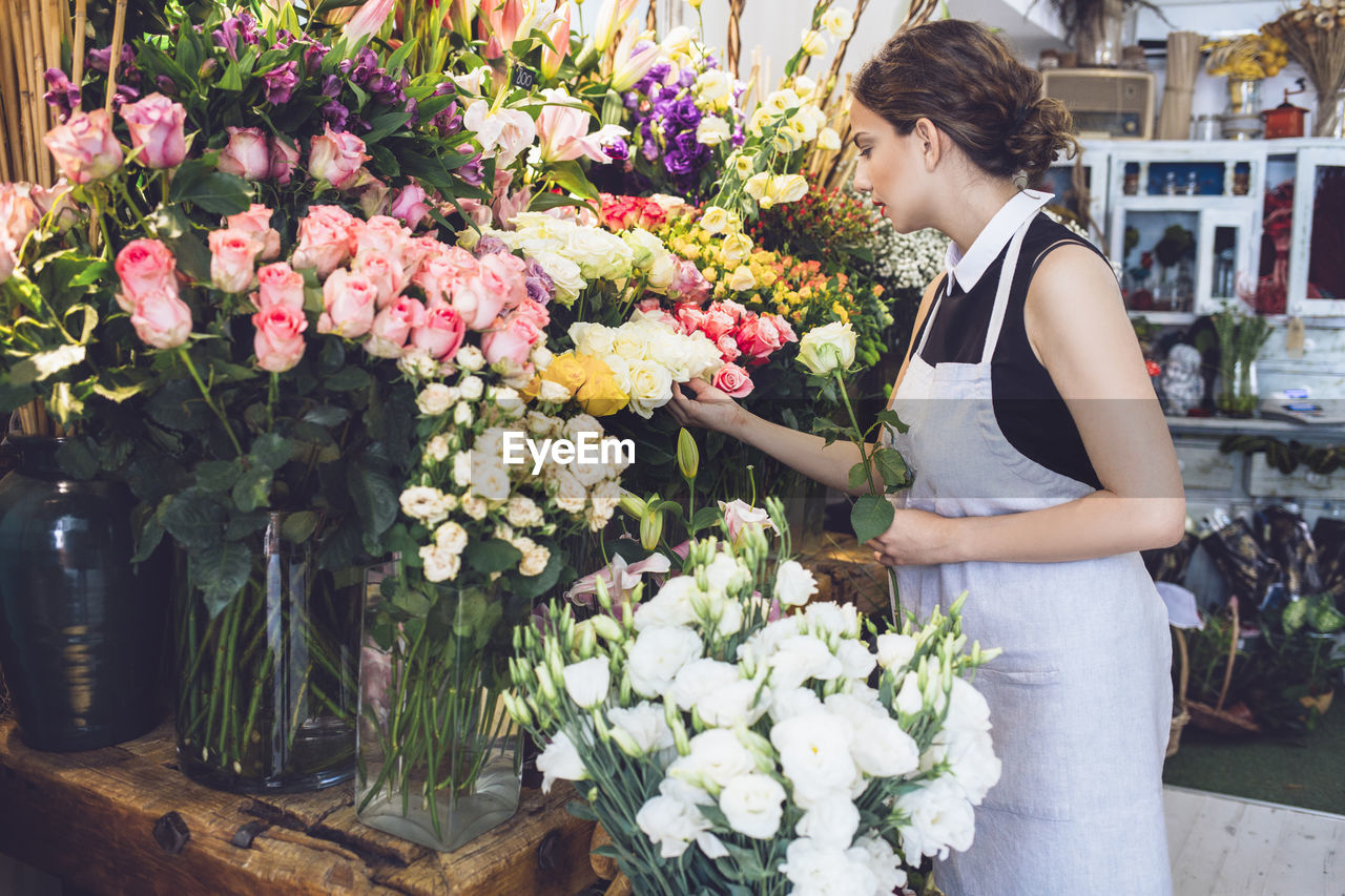 Female florist arranging roses in shop