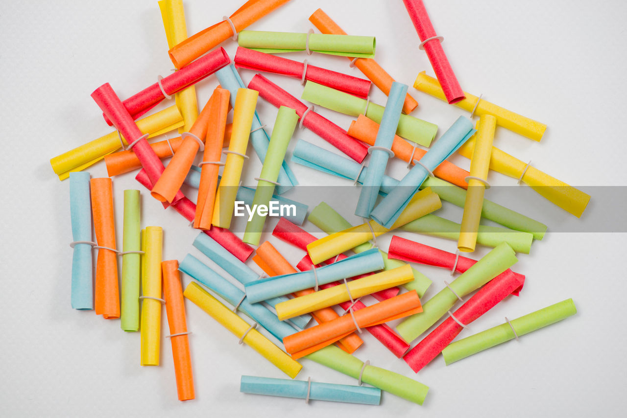 Close-up of multi colored paper rolls against white background