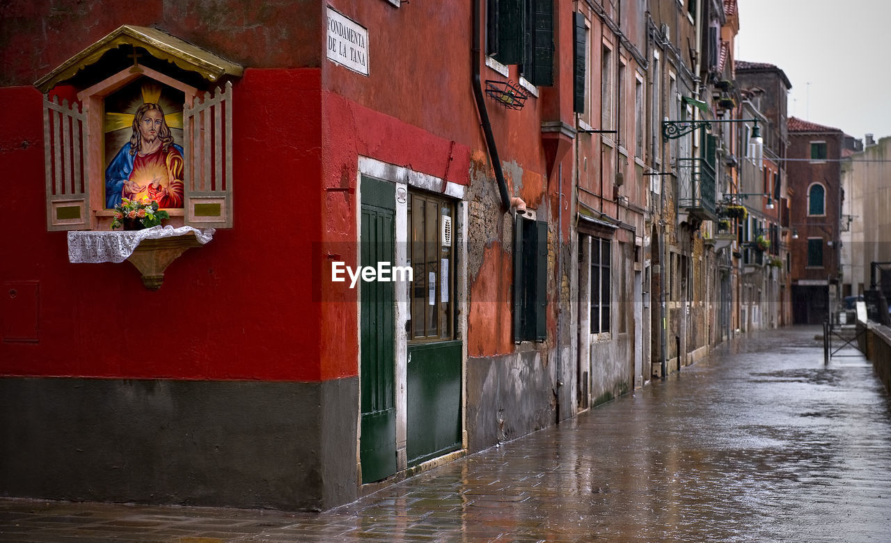 Wet street by buildings at piazza san marco during rainy season