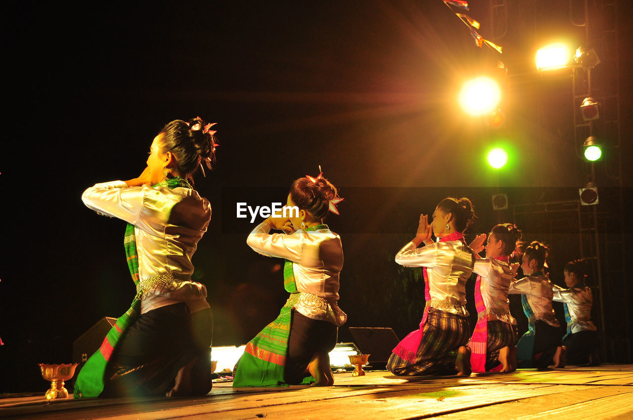 GROUP OF PEOPLE DANCING AT NIGHT DURING FESTIVAL